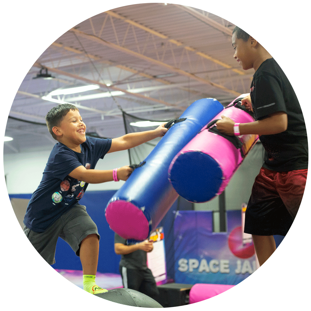 two friends battling it out on our battle beam inside Cosmic Air Trampoline Park located in Houston, TX